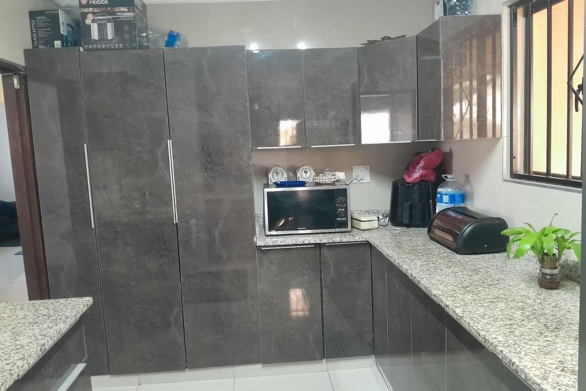 Modern kitchen featuring high-gloss grey cabinetry, granite countertops, and tiled flooring, offering a clean and functional workspace.