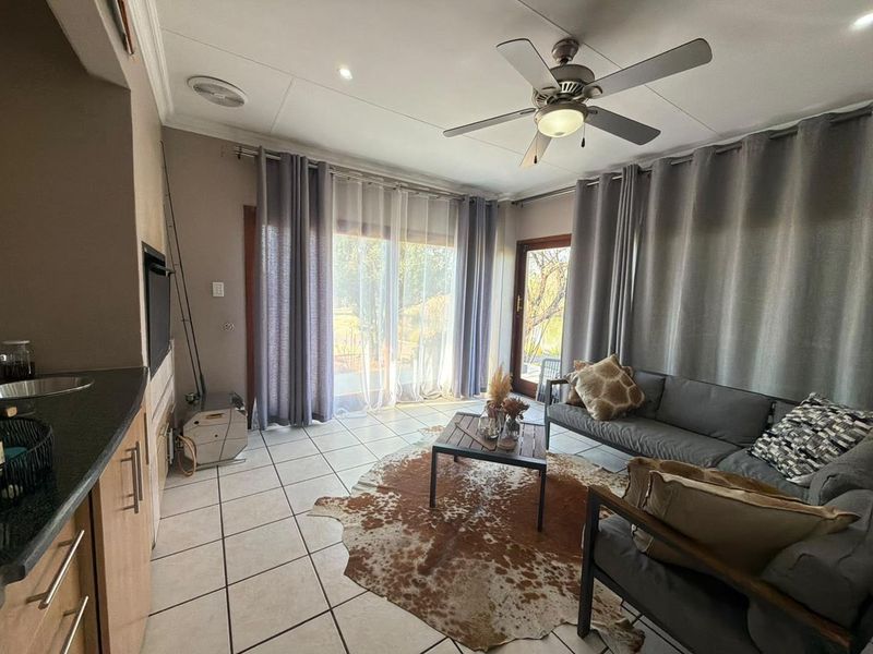 Open plan living area featuring tiled floors, a ceiling fan, and sliding glass doors providing natural light and access to the outdoor space.