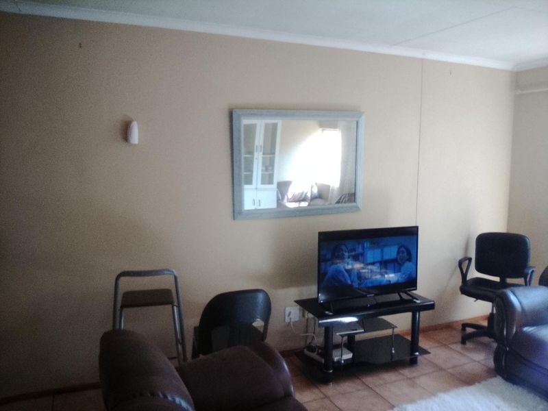 A living room area featuring tiled flooring and a coved ceiling, providing a functional space for relaxation.