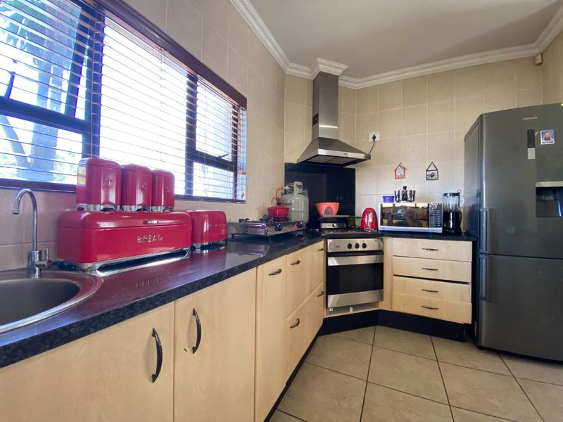 A functional kitchen featuring light wood cabinetry, granite countertops, a stainless steel extractor fan, and a built-in oven with a gas hob.