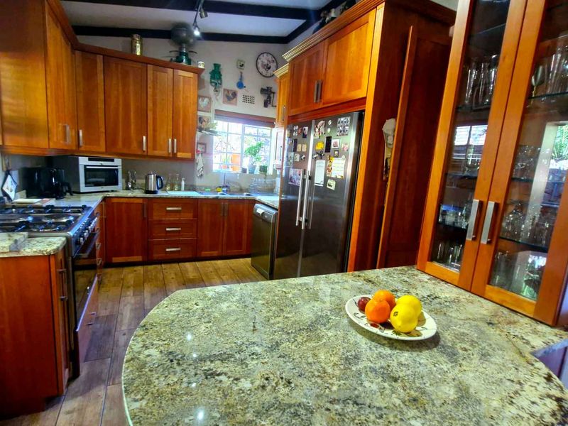 A warm, traditional kitchen featuring extensive wooden cabinetry, granite countertops, a gas stove, and a central island, offering a functional and classic cooking space.