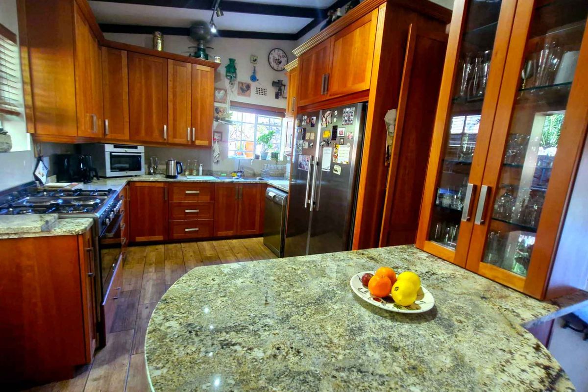 A warm, traditional kitchen featuring extensive wooden cabinetry, granite countertops, a gas stove, and a central island, offering a functional and classic cooking space.