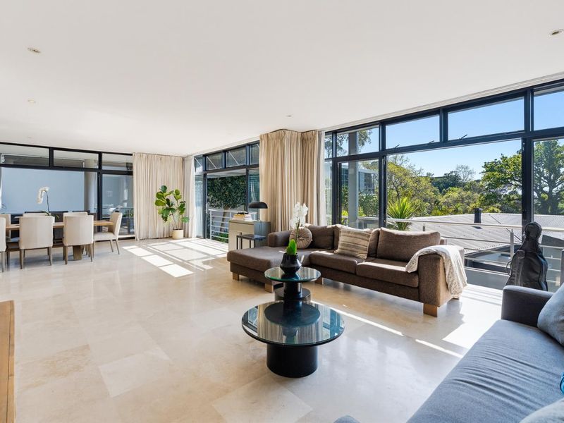 Spacious open-plan living and dining area featuring large floor-to-ceiling windows, stone tile flooring, and seamless access to the outdoor balcony.