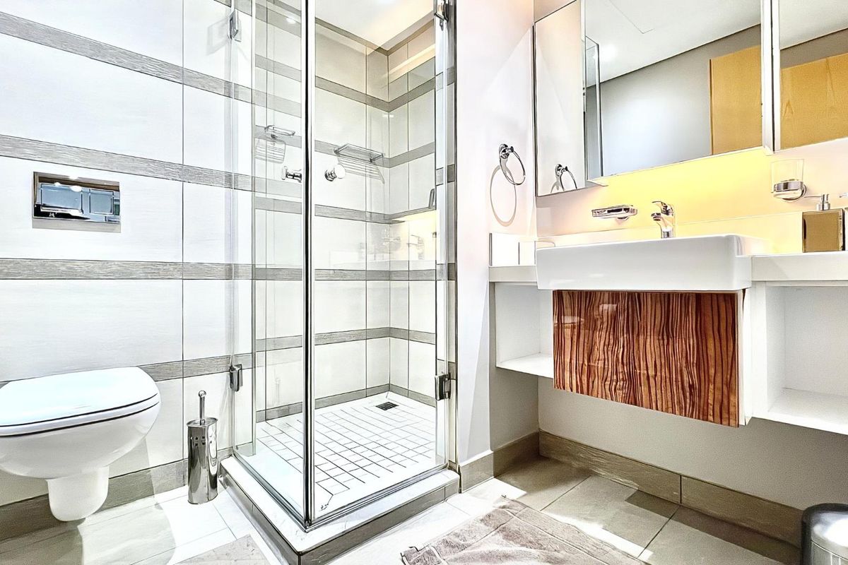 Modern bathroom featuring a glass shower enclosure, wall-mounted toilet, and a floating vanity with a basin and mirrored cabinet.