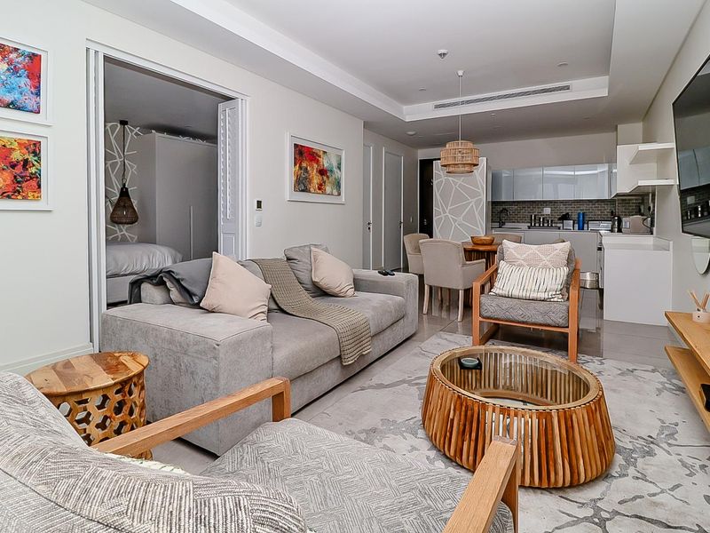 Modern open-plan living area featuring tiled floors, recessed ceiling lighting, ducted air conditioning, and a sleek integrated kitchen with a tiled backsplash.