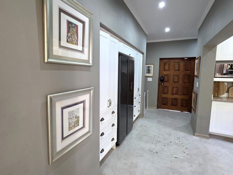A functional kitchen area featuring built-in white cabinetry, integrated appliances, recessed ceiling lighting, and a solid wood entrance door.