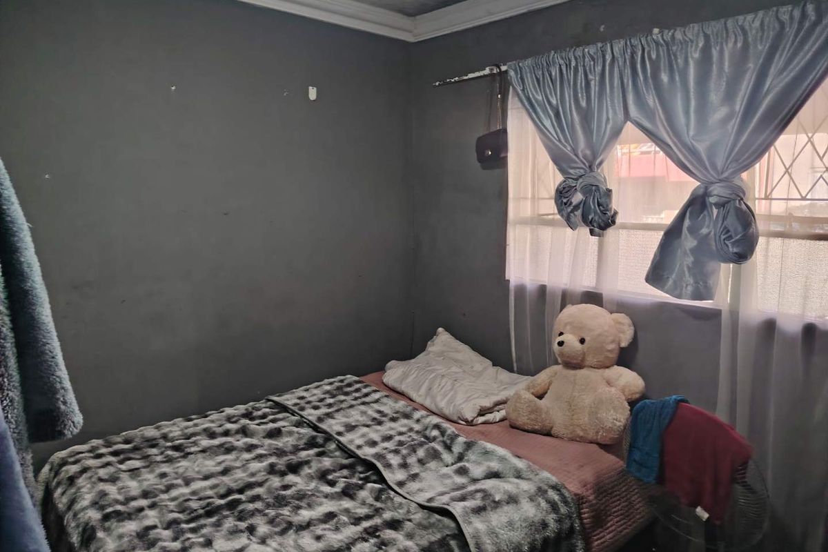 A bedroom featuring dark grey walls, crown molding, and a window with fitted security bars.