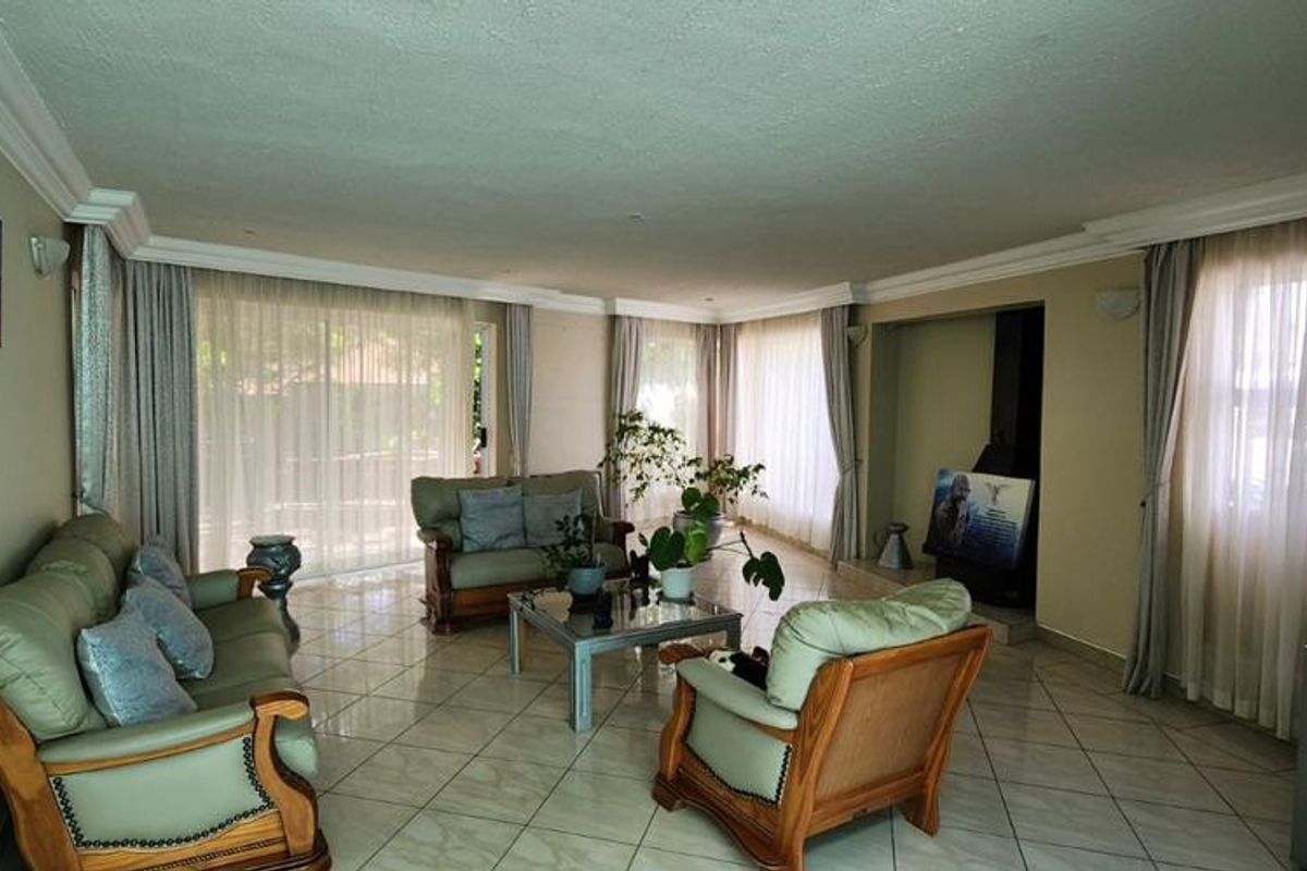 Spacious living room featuring tiled flooring, crown molding, and a built-in fireplace, with large windows providing ample natural light.