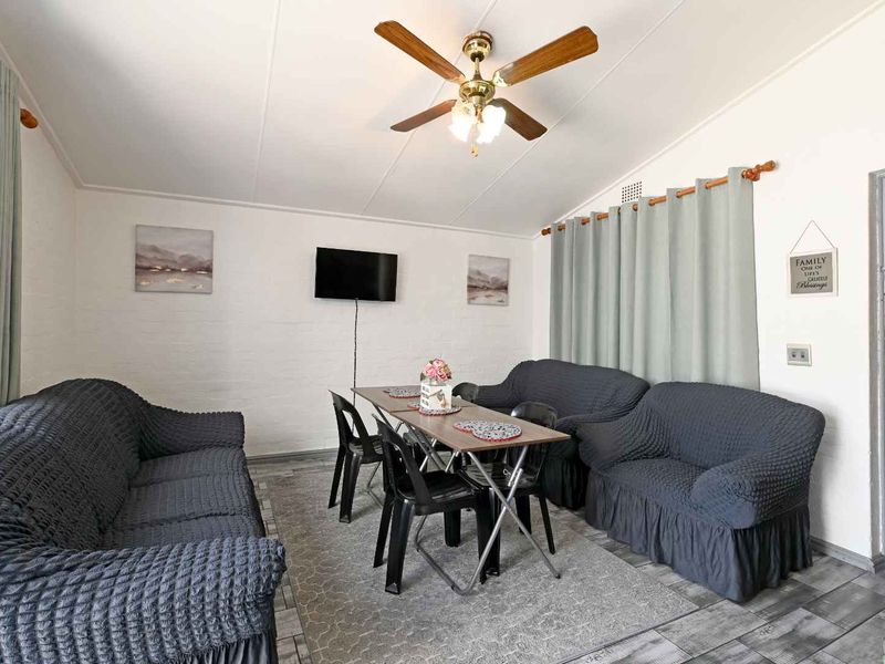 A functional living area featuring tiled flooring, painted brick walls, and a ceiling fan, providing a versatile space for relaxation and dining.