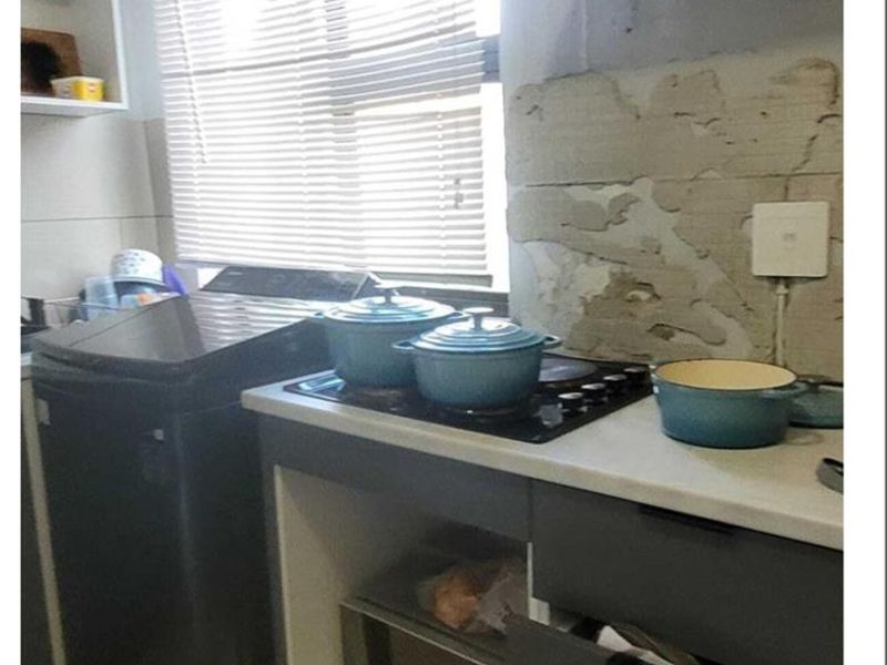 Compact kitchen area featuring a built-in hob and microwave, requiring wall repairs and finishing to improve the overall aesthetic and functionality.