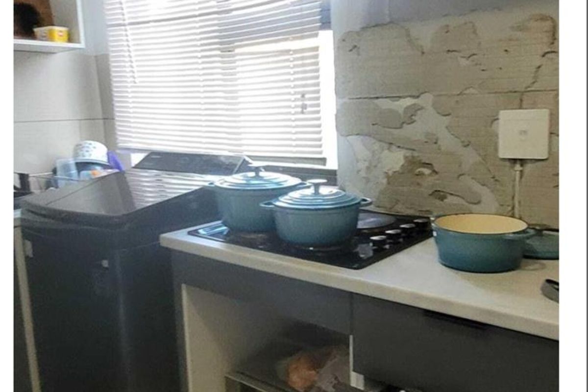 Compact kitchen area featuring a built-in hob and microwave, requiring wall repairs and finishing to improve the overall aesthetic and functionality.