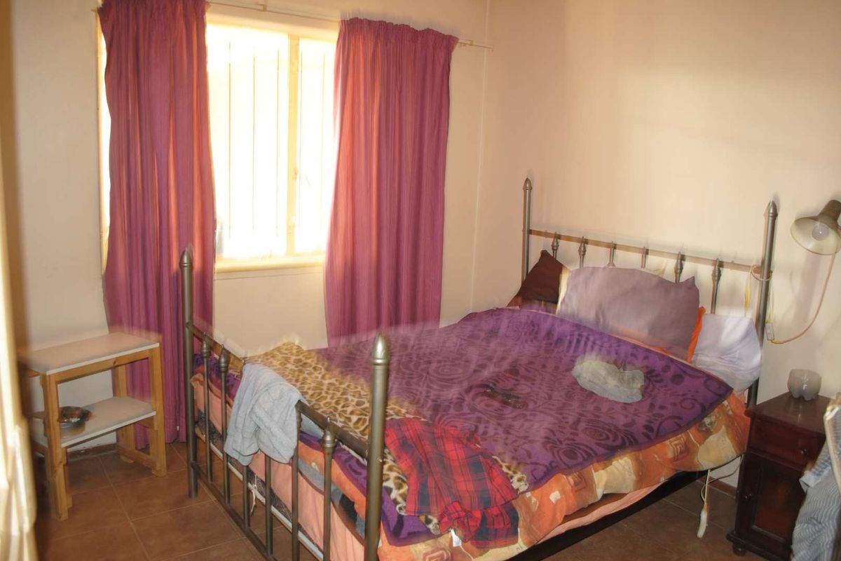 A bedroom featuring tiled flooring and a window with curtains, providing a functional space for rest.