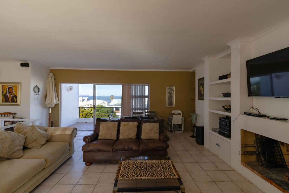 Spacious living room featuring tiled flooring, a built-in fireplace with shelving, and sliding glass doors leading to an outdoor patio with ocean views.