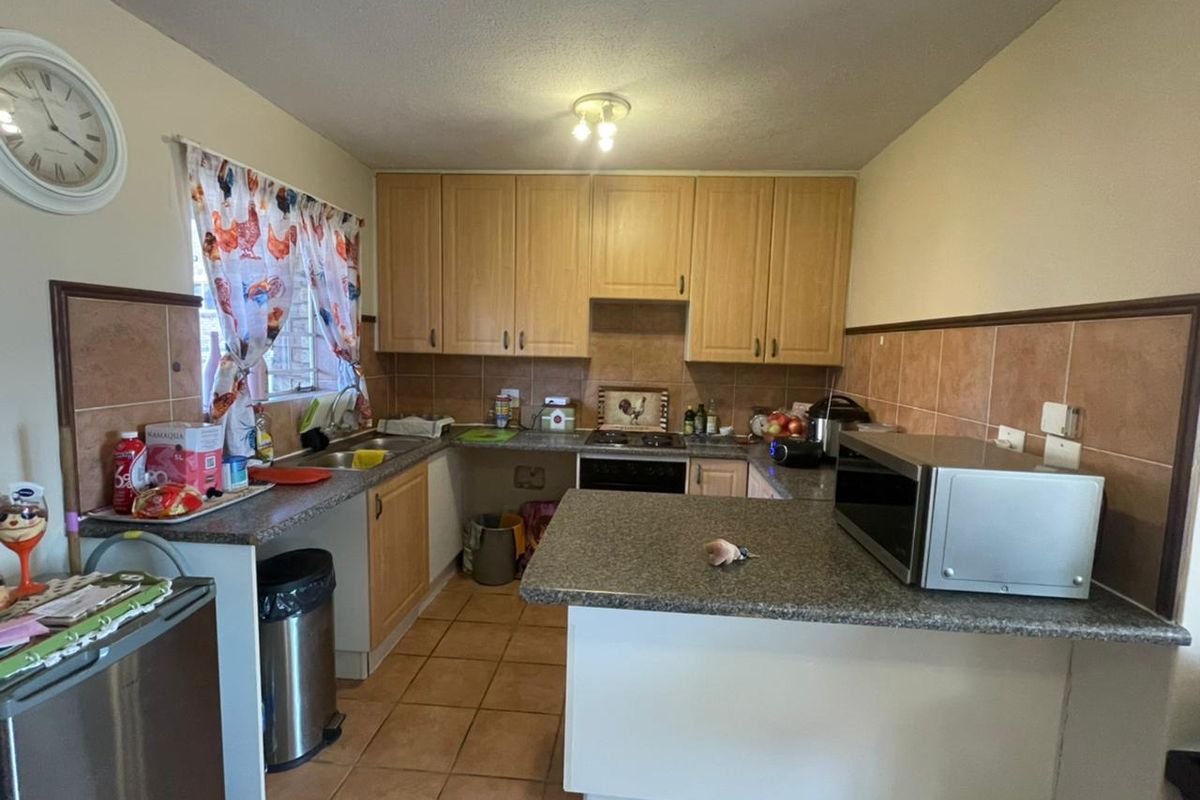 Functional kitchen featuring light wood cabinetry, granite-look countertops, tiled splashbacks, and a breakfast bar peninsula.