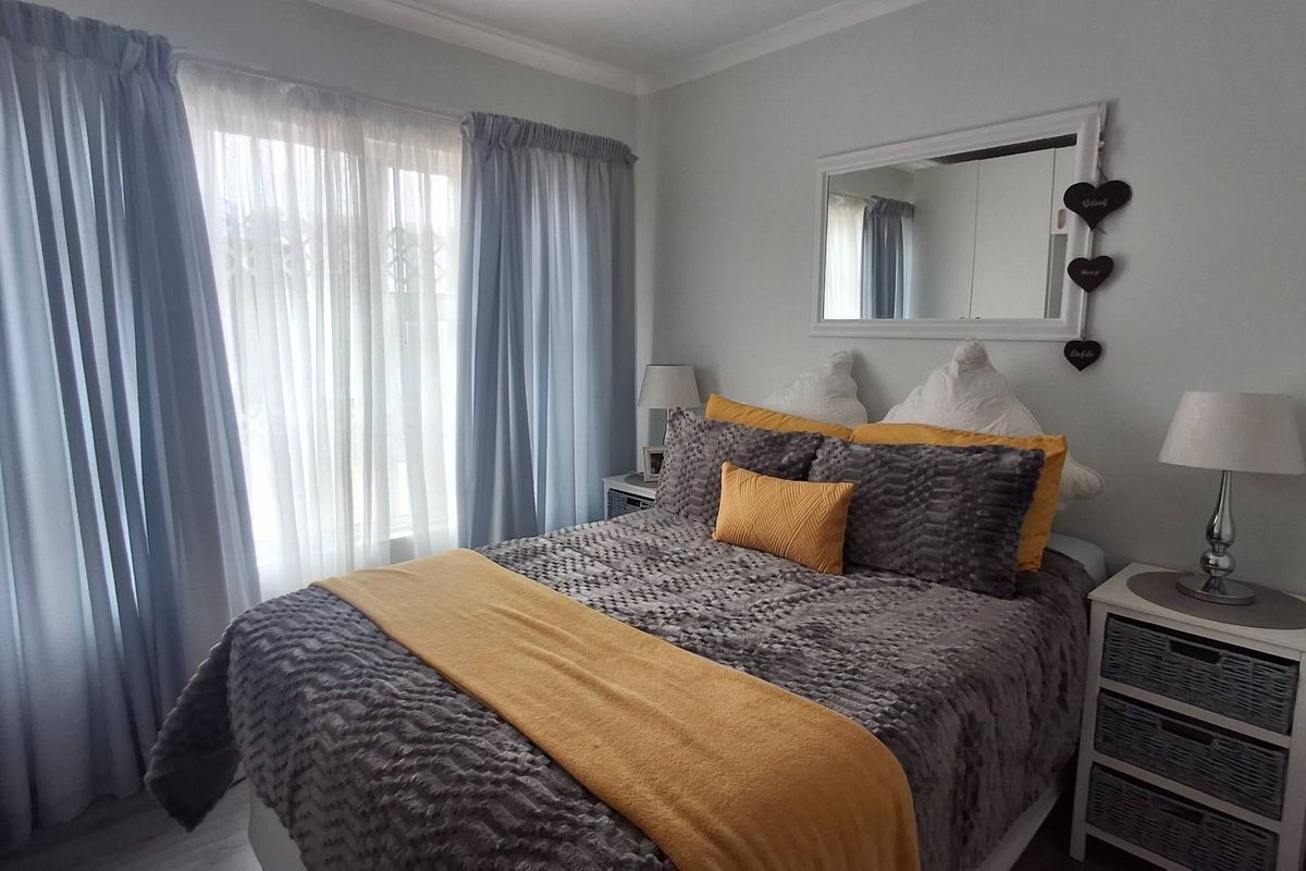 A well-maintained bedroom featuring neutral wall finishes, natural light through large windows, and integrated storage cabinetry.