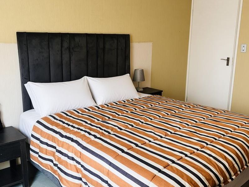 A bedroom featuring tiled flooring and neutral wall finishes, providing a functional space with direct access to an internal door.