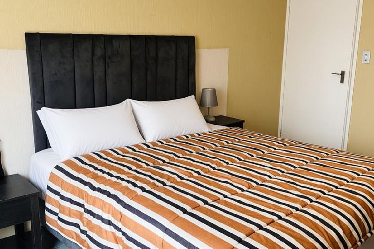 A bedroom featuring tiled flooring and neutral wall finishes, providing a functional space with direct access to an internal door.