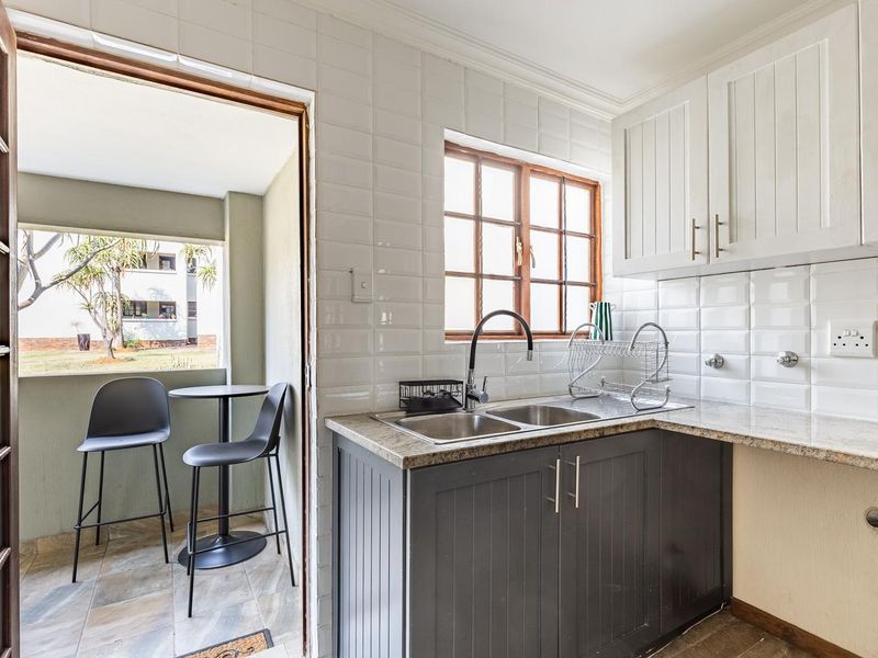 A well-maintained kitchen featuring modern shaker-style cabinetry, granite countertops, a double basin sink, and a classic subway tile backsplash with natural light.