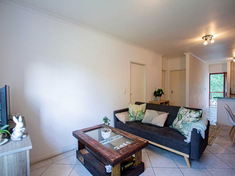 Open plan living and dining area featuring tiled flooring and a functional kitchen layout with a breakfast bar.