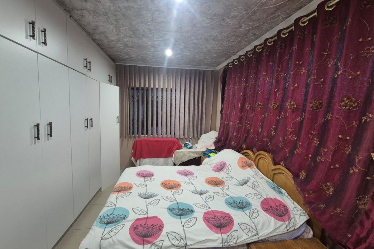 A bedroom featuring extensive built-in cupboard storage, tiled flooring, and recessed ceiling lighting.