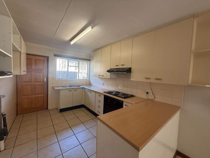 A functional kitchen featuring built-in cabinetry, laminate countertops, an electric hob, and an oven, with tiled flooring and a tiled backsplash.