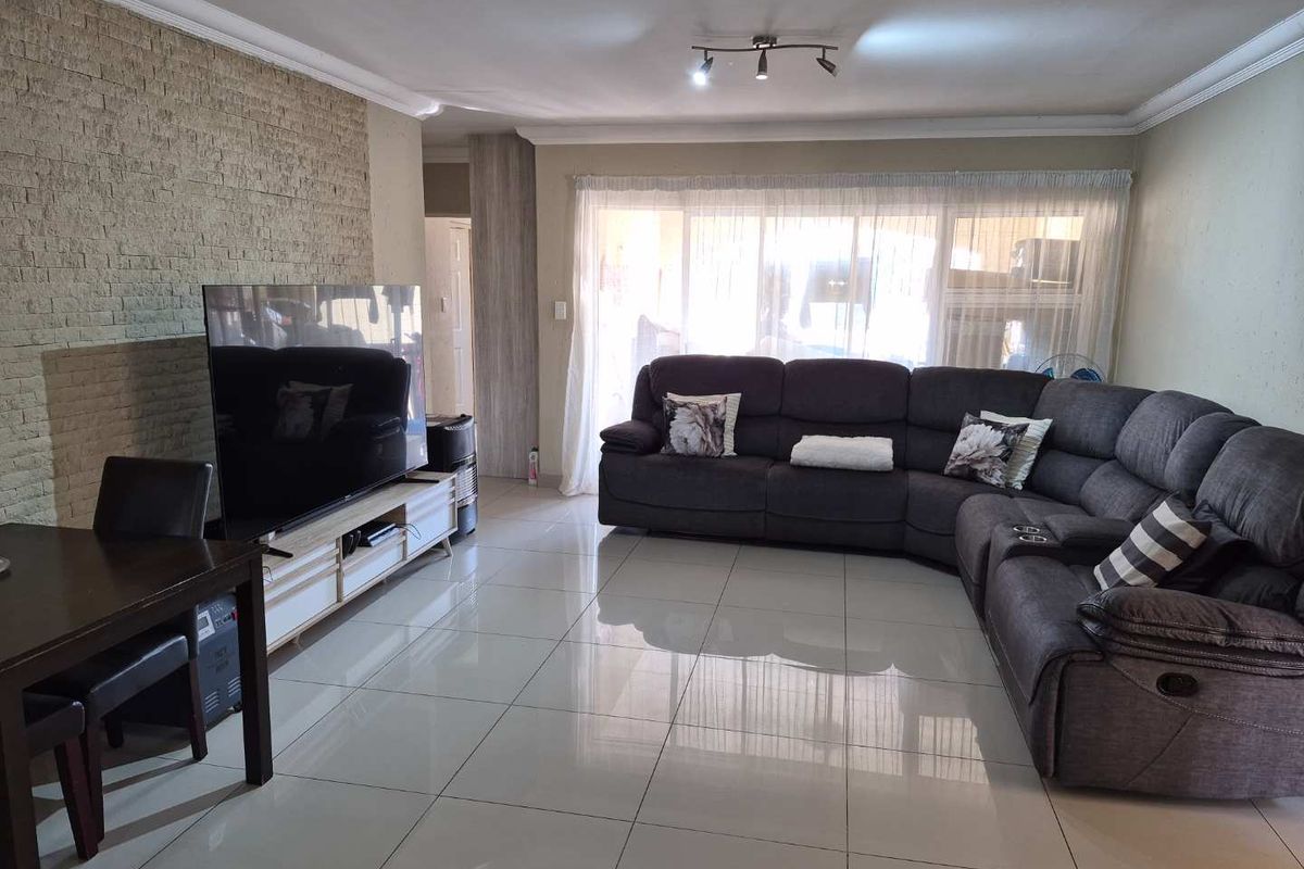 Spacious living room featuring polished porcelain floor tiles, a textured stone feature wall, and ceiling coving, providing a modern and comfortable living space.