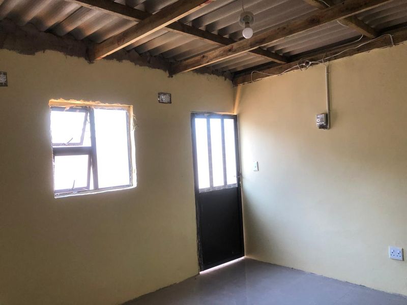 An empty bedroom featuring exposed timber roof beams, tiled flooring, and basic finishes, offering a blank canvas for renovation and interior design improvements.