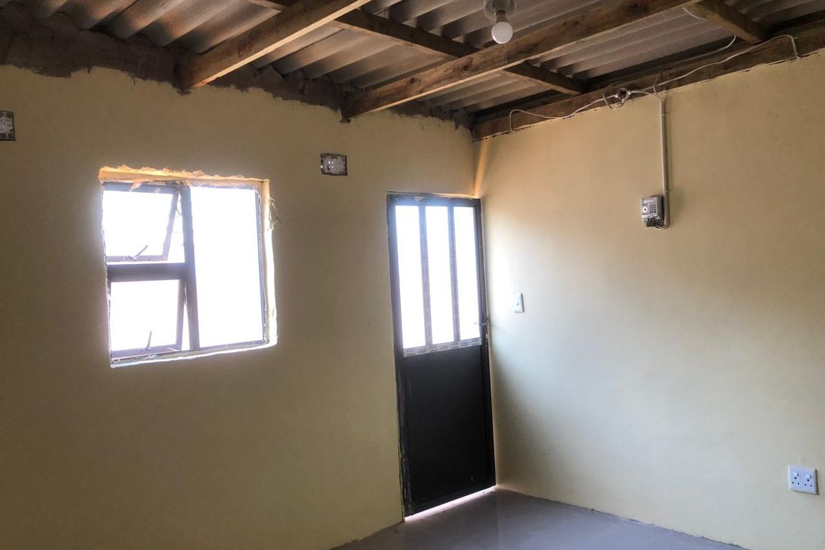 An empty bedroom featuring exposed timber roof beams, tiled flooring, and basic finishes, offering a blank canvas for renovation and interior design improvements.