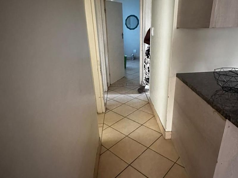 A functional hallway featuring tiled flooring and built-in cabinetry, providing access to adjacent rooms within the home.