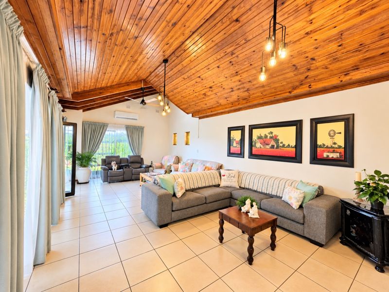 Spacious living room featuring a high vaulted timber ceiling, neutral tiled flooring, and large sliding glass doors providing ample natural light.