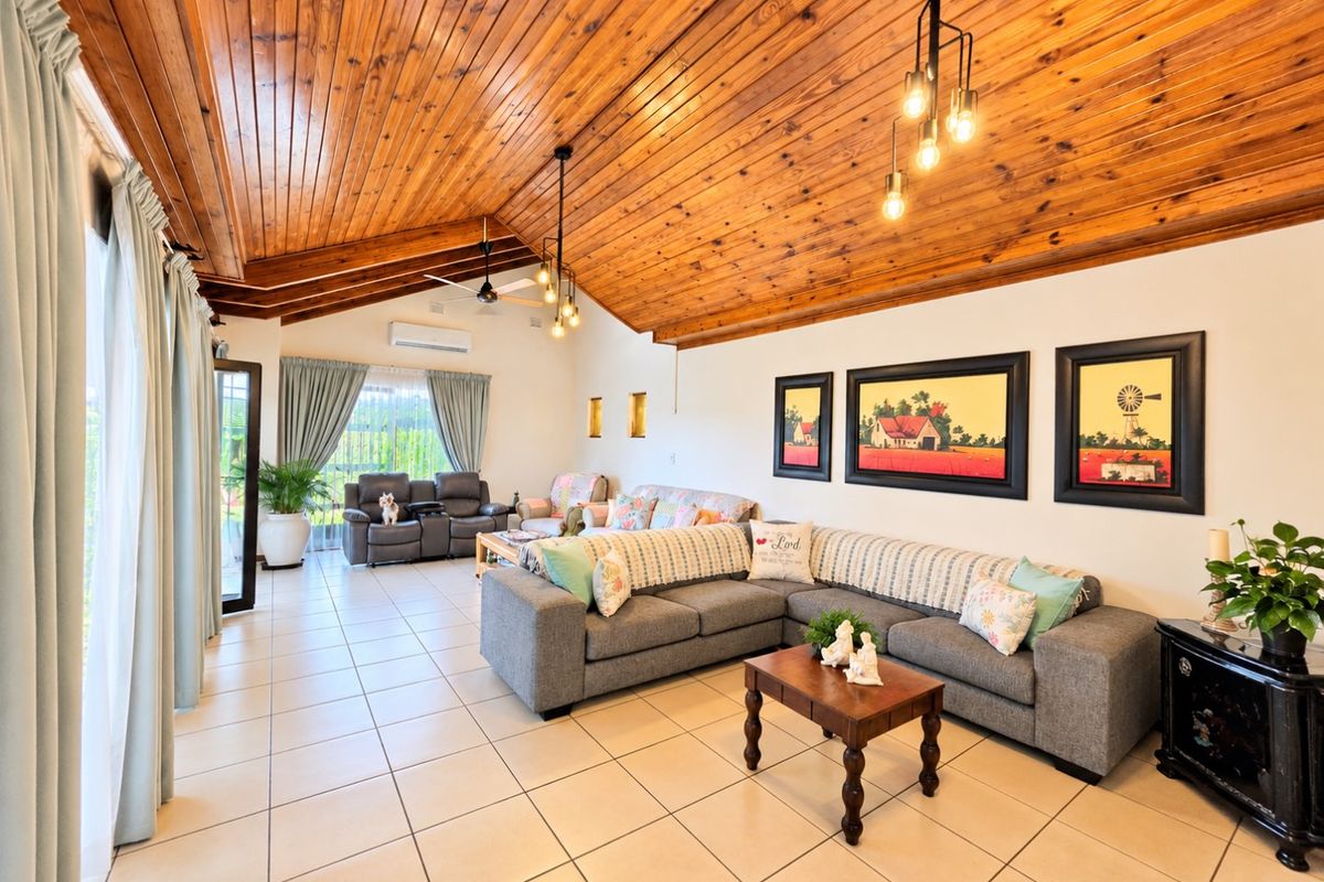 Spacious living room featuring a high vaulted timber ceiling, neutral tiled flooring, and large sliding glass doors providing ample natural light.
