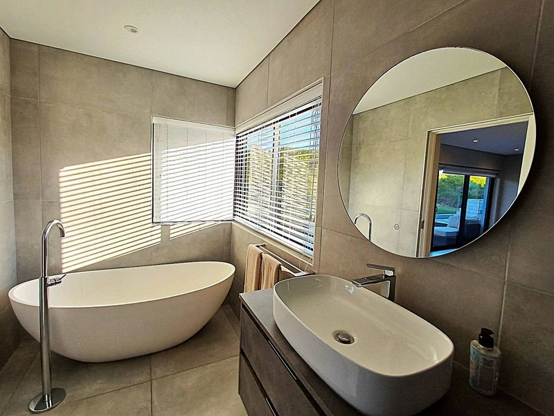 Modern bathroom featuring a sleek freestanding bathtub, a contemporary vessel sink on a vanity cabinet, and large-format wall tiles with natural light.