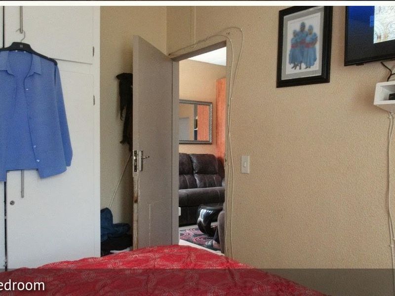 A bedroom featuring a built-in wardrobe and an internal doorway leading to an adjacent living space.