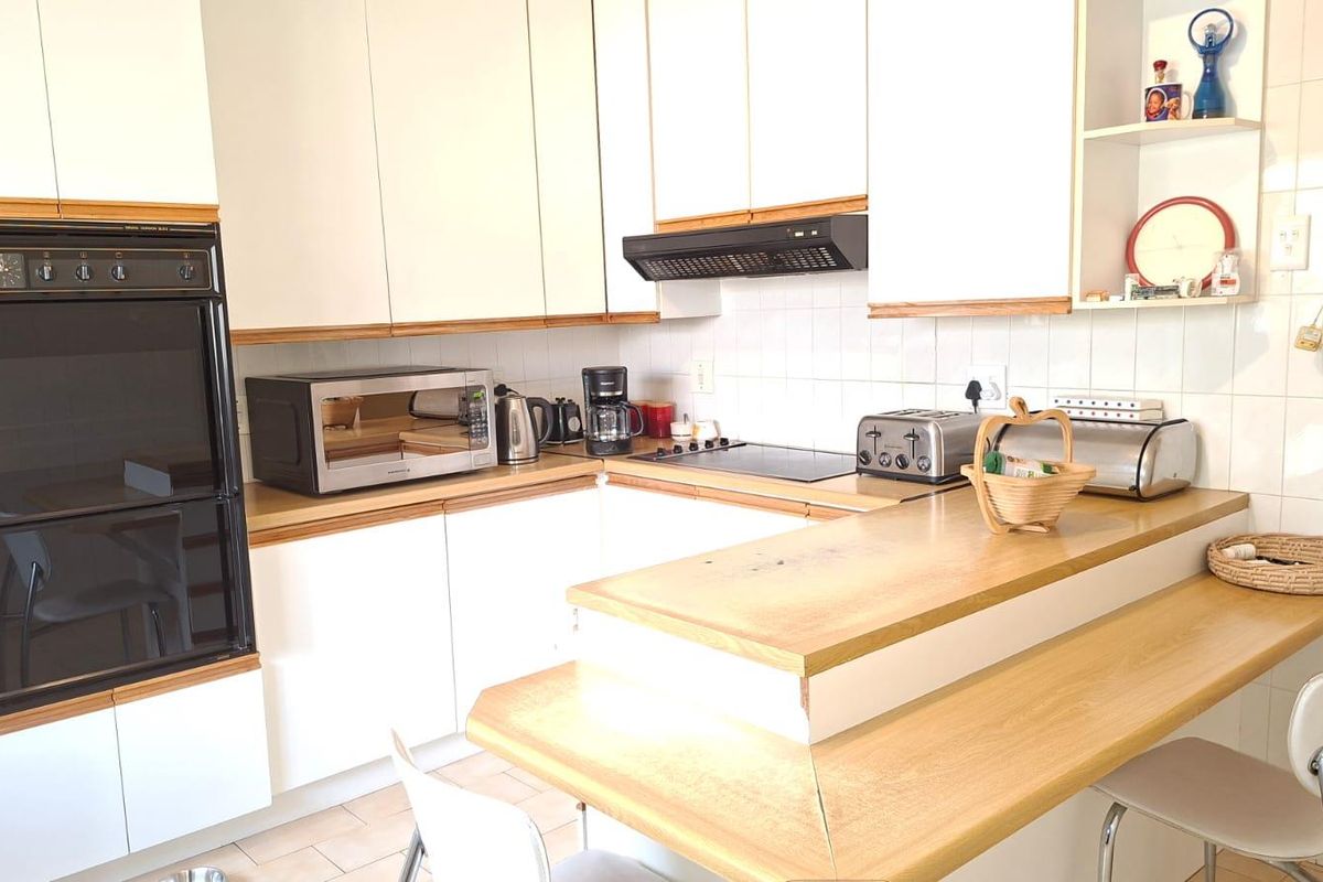 A functional kitchen featuring white cabinetry, laminate countertops, a built-in oven, and a tiled splashback, offering a practical layout for daily meal preparation.