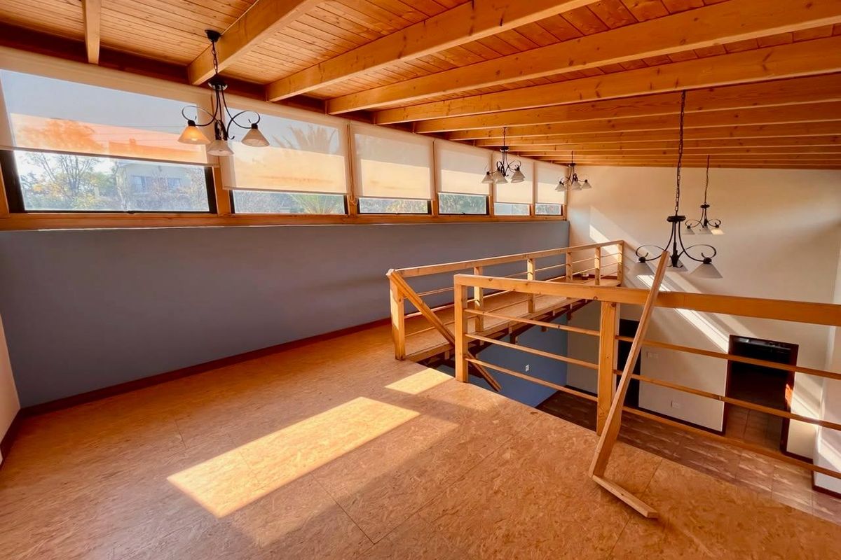 Spacious mezzanine living area featuring exposed timber beam ceilings, timber flooring, and large clerestory windows providing ample natural light.