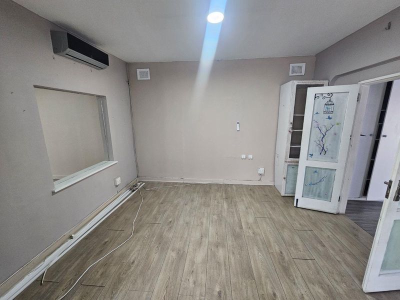 An empty bedroom featuring laminate flooring, an installed air conditioning unit, and recessed lighting, ready for a fresh update.