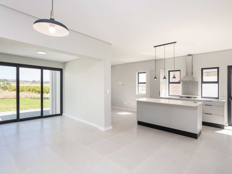 Modern open-plan kitchen and living area featuring sleek cabinetry, a central island, and large sliding doors opening to a garden view.