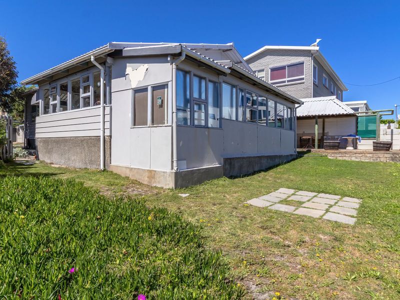 Rear view of the property showing the exterior facade, aluminium windows, and a small garden area with paved stepping stones.