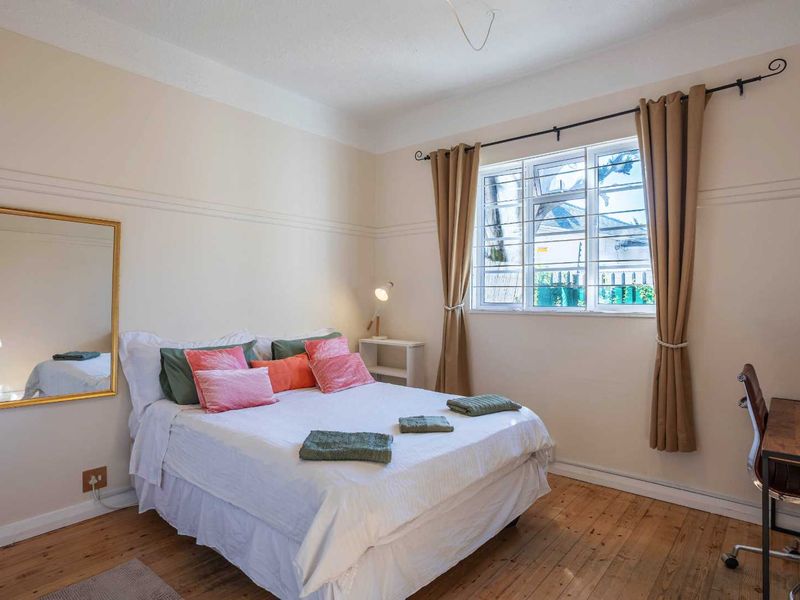 A bedroom featuring original timber flooring, a picture rail, and a window fitted with security bars.