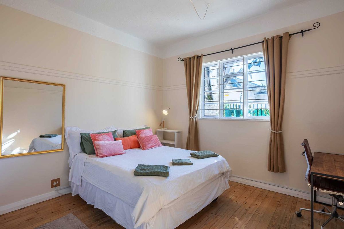 A bedroom featuring original timber flooring, a picture rail, and a window fitted with security bars.