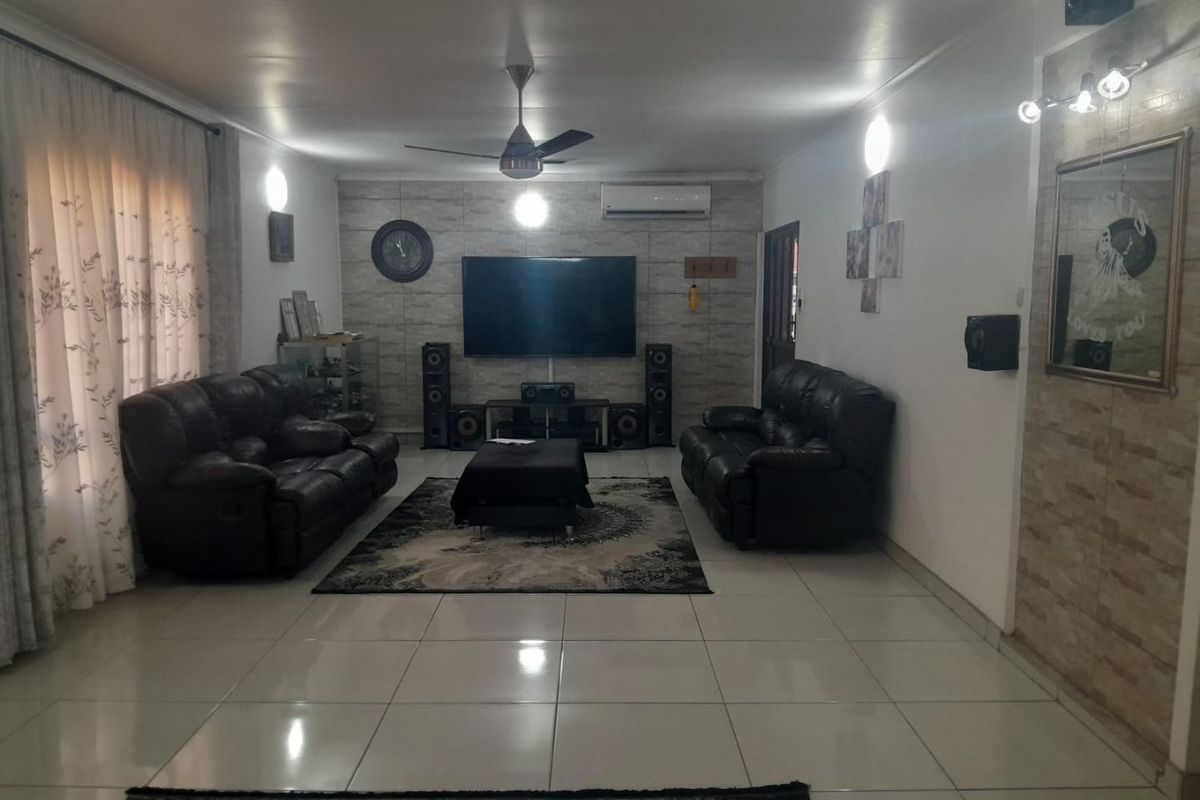Spacious living room featuring large format floor tiles, a stone-cladding feature wall, and a ceiling fan for climate control.