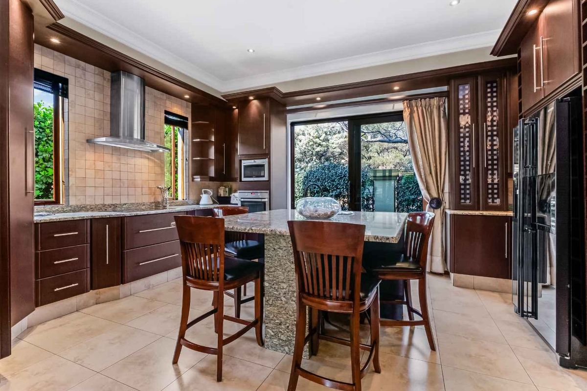 Spacious kitchen featuring dark wood cabinetry, granite countertops, a central island with seating, and direct access to the outdoor area through sliding glass doors.