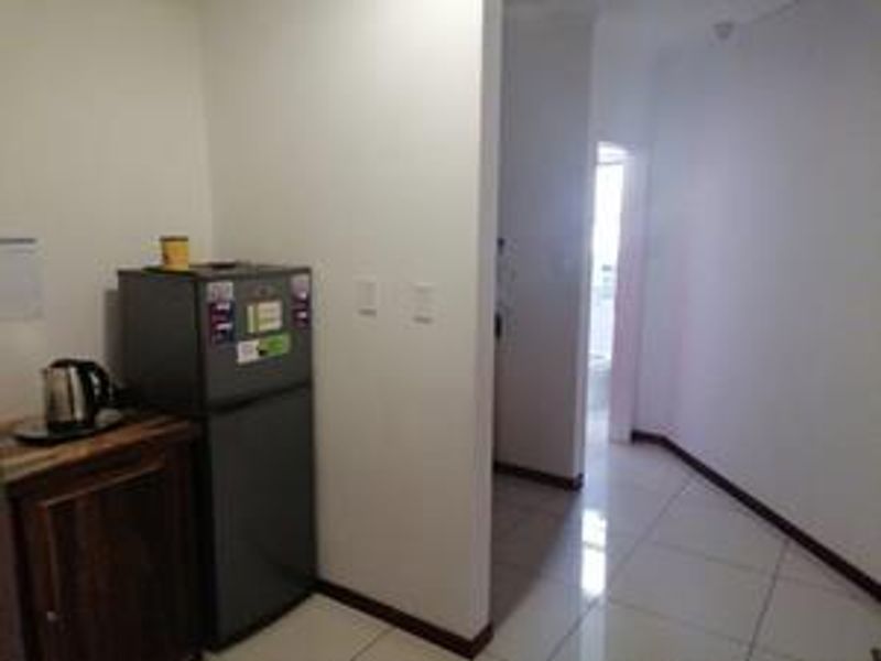 A compact kitchenette area featuring tiled flooring and built-in cabinetry, providing a functional space for office refreshments.