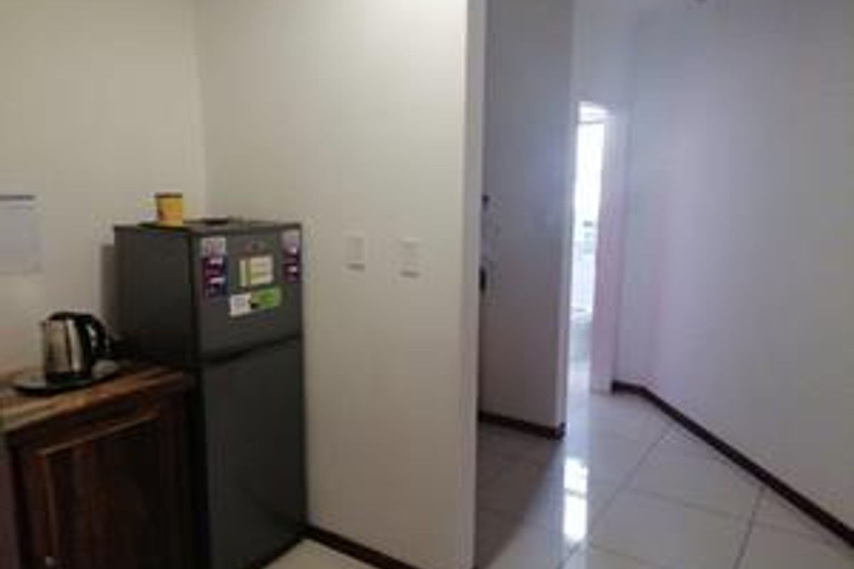 A compact kitchenette area featuring tiled flooring and built-in cabinetry, providing a functional space for office refreshments.