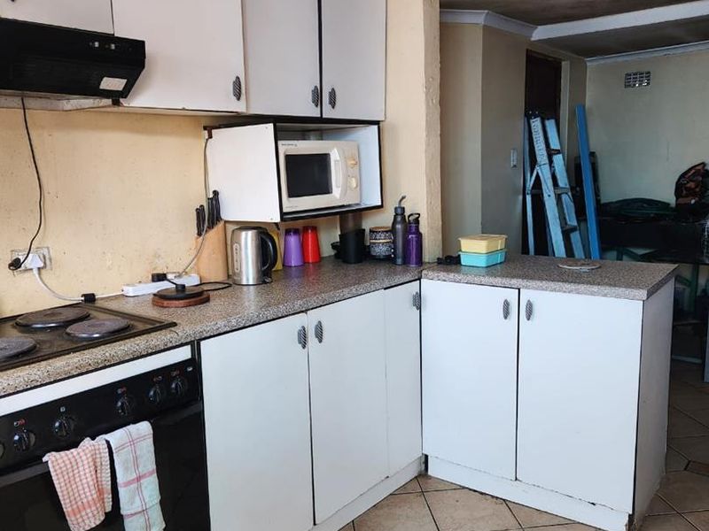 A functional kitchen featuring laminate countertops, built-in cabinetry, and an electric stove, requiring cosmetic updates to improve its overall condition and aesthetic appeal.