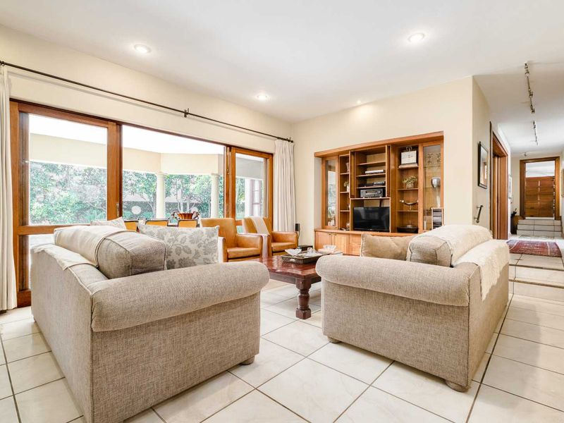 Spacious living room featuring tiled flooring, recessed lighting, and a large built-in wooden display unit, with direct access to the patio through sliding glass doors.