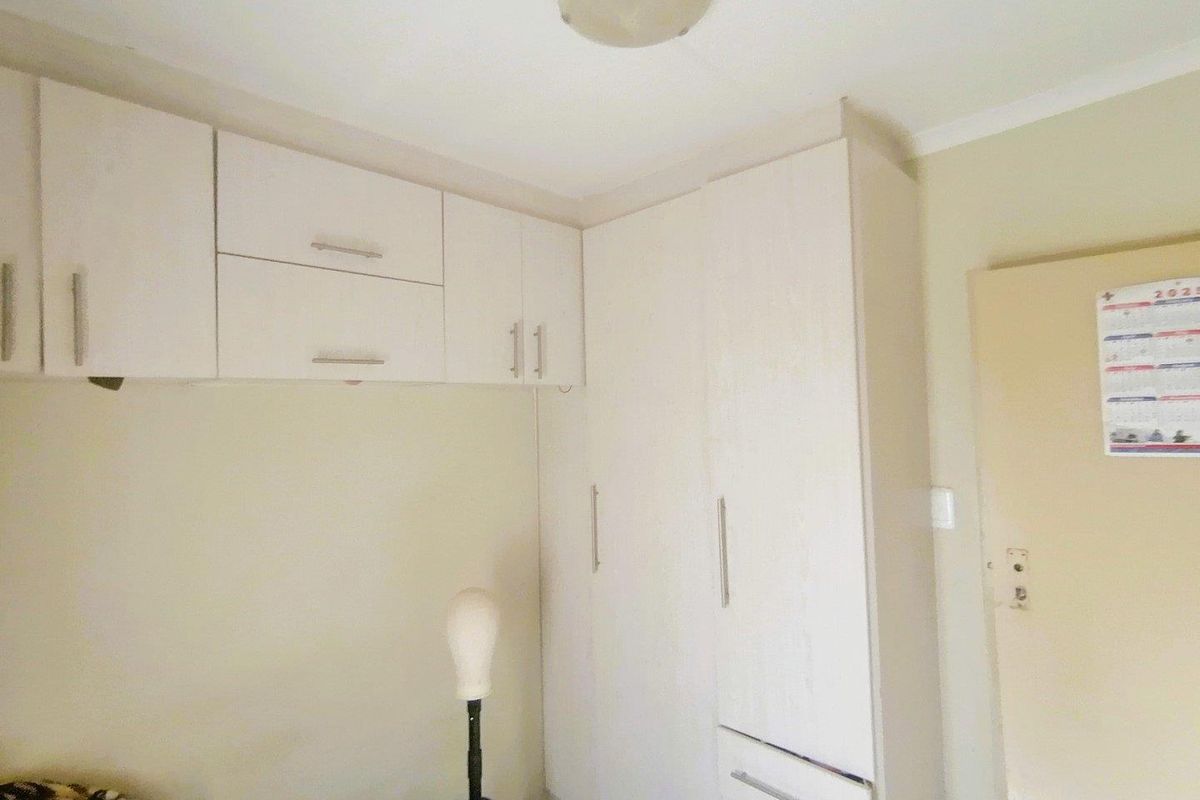 A bedroom featuring built-in cupboards and overhead storage cabinets, providing functional storage space.