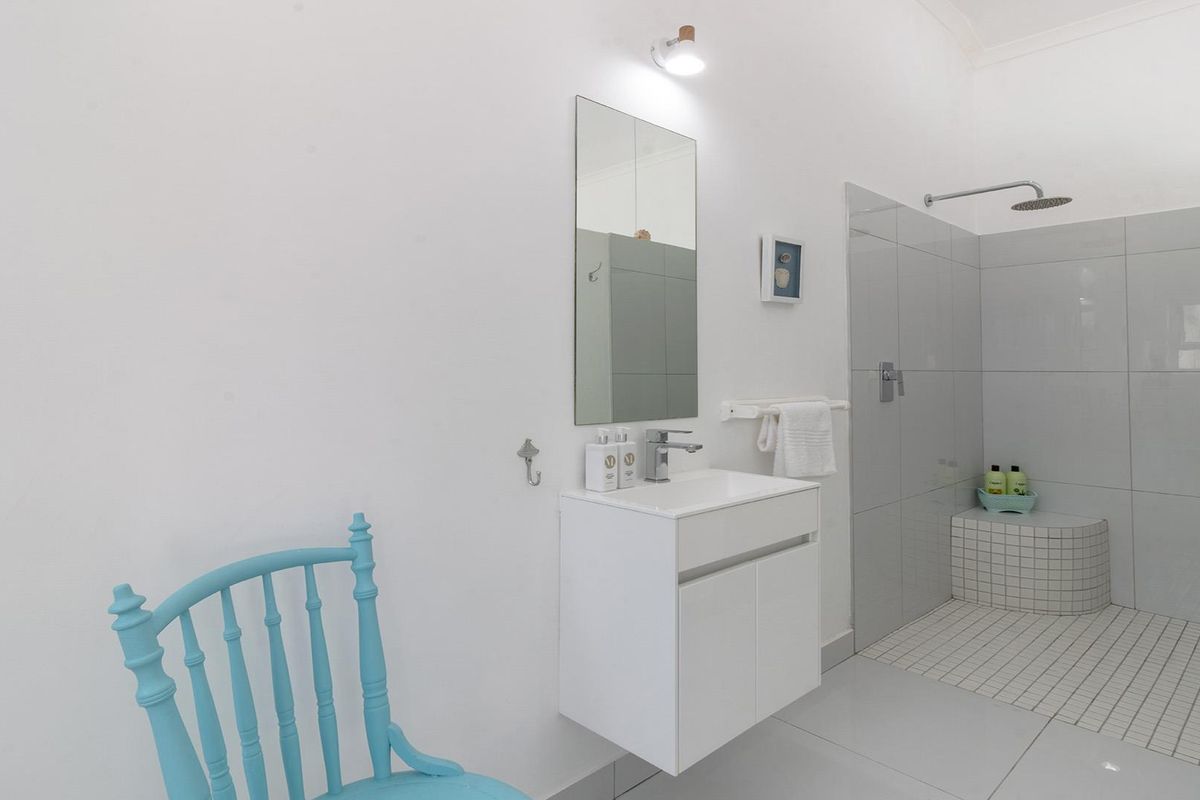 Modern bathroom featuring a wall-mounted vanity, basin, and a spacious walk-in shower with a built-in tiled bench and rain shower head.