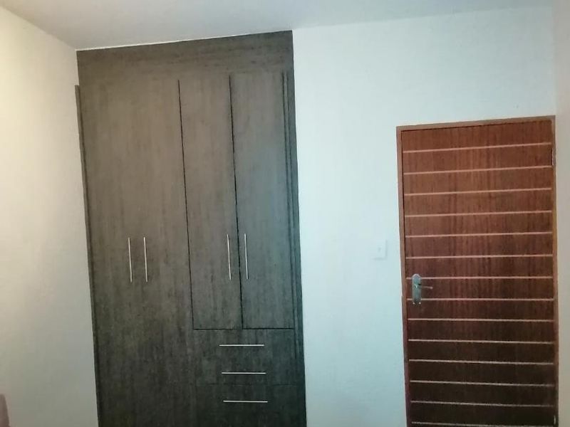 A bedroom featuring a dark wood built-in wardrobe and a horizontal slatted internal door.