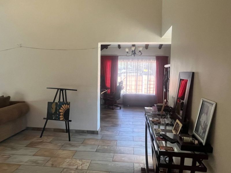 Spacious living area featuring tiled flooring and a vaulted ceiling, with an open transition to an adjacent room.